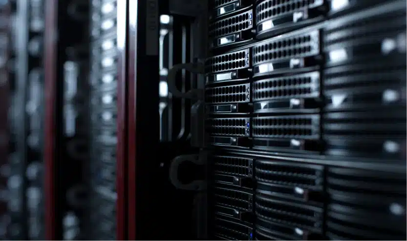 Close-up view of stacked black server racks illuminated by low lighting inside a data center