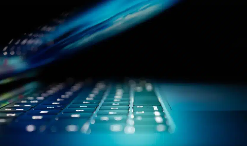 Close-up of laptop keyboard backlighting reflecting a futuristic tech atmosphere under low light