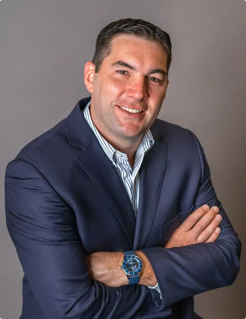 Professional headshot of a smiling business executive wearing a dark blue blazer and striped shirt
