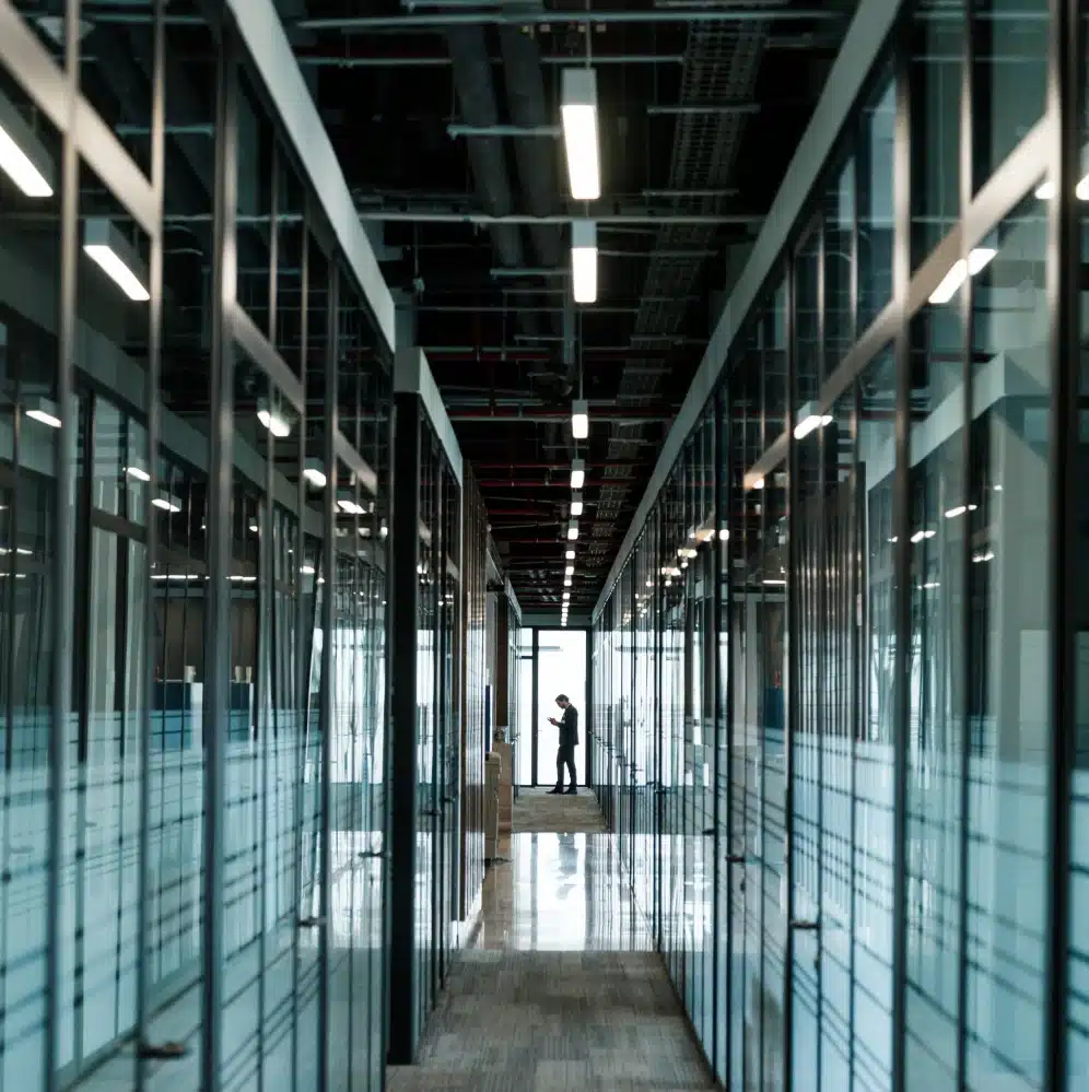 Business professional using a device while walking through a high-tech corporate office corridor